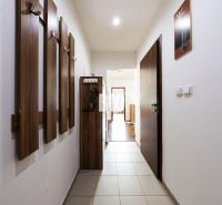 A hallway with a coat rack and tiles leads to a 3-room apartment.