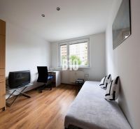 A room in a 3-room apartment with a wooden decor floor, a sofa, and a desk.