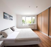 A bright bedroom in a 3-room apartment with a large wardrobe and a wooden decor floor.