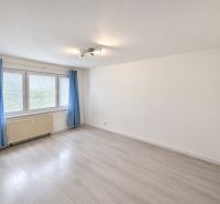 A bright room with blue curtains and a wood-patterned floor in a three-room apartment.