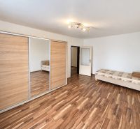 Bedroom in a 3-room apartment with a bed, wardrobe, and floor with wooden decor.