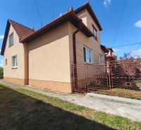 A family house in Oslany with a red roof and a wrought iron gate on the property.