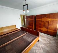 A bedroom in a family house with a wooden decor floor, beds, and wardrobes.
