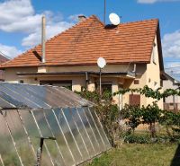 Family house in Oslany, greenhouse, satellite dishes, garden with a fence, blue sky.