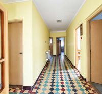 A hallway in a family house with colorful tiles and wooden doors.