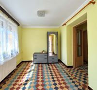 A room with a patterned floor, light yellow walls, and a window with curtains in a family house.