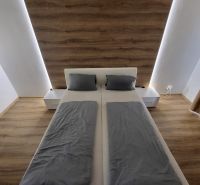 A bedroom with a light-colored bed, gray bedding, and a wooden-patterned floor in a 4-room apartment.