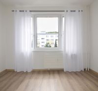 A bright room with a wood-decor floor in a 4-room apartment with curtains.