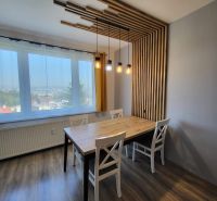 Dining area in a 4-room apartment with wood-patterned flooring and designer lighting.