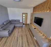Living room with a large sofa and television in a 4-room apartment, floor with wood decor.