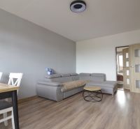 Living room with a gray sofa, table, and floor with a wood decor in a 4-room apartment.