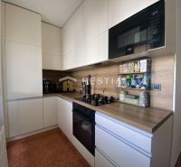 A kitchen in a 2-room apartment with white cabinets and a wooden decor.