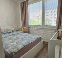 Bedroom in a two-room apartment with large windows and a wooden decor floor.