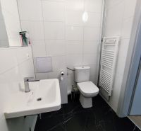 White bathroom with toilet and black floor in the office.