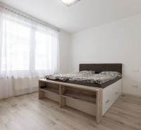 A bright bedroom with retractable curtains, a bed, and a wooden decor floor in a 2-room apartment.