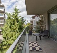 A balcony of a 2-room apartment with a view of greenery and neighboring buildings.