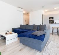 Living room with a blue sofa, white table, and kitchen in a two-room apartment.
