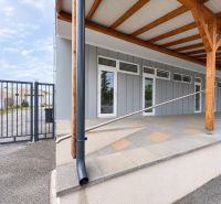 Commercial premises in Komárno with interlocking paving, wooden columns, and a metal gate.