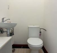 Restroom in commercial premises, with a sink and simple furnishings.