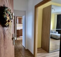 A hallway with tiles next to a floor with a wooden decor in a 3-room apartment.