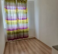 A small room in a 3-room apartment with a wood-patterned floor and colorful curtains.