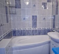 A bathroom with a corner bathtub, blue and white tiles in a 3-room apartment.