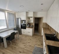 A kitchen in a 3-room apartment with a wooden decor floor and light furniture.