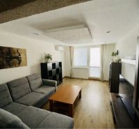 Living room with a large sofa and wooden decor flooring in a 3-room apartment.