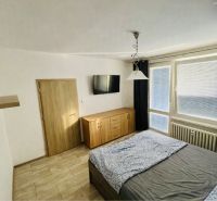 A bedroom with a wood-patterned floor, a bed, a dresser, and a television in a 3-room apartment.