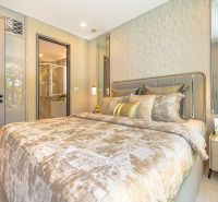 A stylish bedroom in a vacation apartment with an elegant bed and light shades.