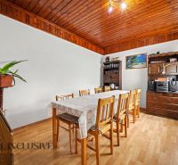 Dining room in a family house with a solid table, wooden decor flooring, and furniture.