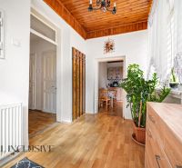 A hallway in a family house with a wooden decor floor, plants, and a view into the kitchen.