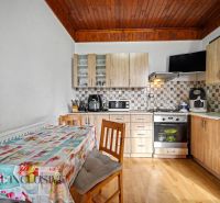A kitchen in a family house with wooden decor on the floor and kitchen cabinets.