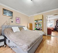 A bedroom in a family house with a wooden decor floor, equipped with a bed and shelves.