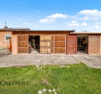 A family house in Povoda with a garage, wooden gates, and a yard with a lawn.