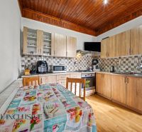 A kitchen in a family house with a wooden countertop, a floor with a wooden decor, and a dining table.