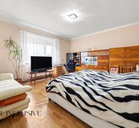 Bedroom with a bed, chair, television, and wooden floor decor in a family house.