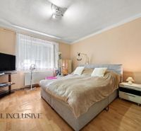Bedroom in a family house with wood-patterned flooring, a television, and a bed.