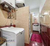 Bathroom in a family house with a washing machine and a shower, surrounded by tiles.