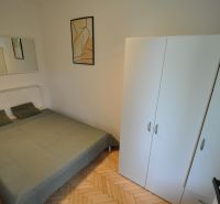 Bedroom in a 2-room apartment with a double bed and a wardrobe, floor with wooden decor.