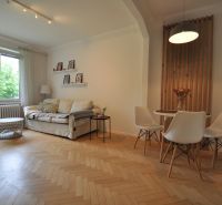 Living room with wood-patterned flooring, a sofa, and a dining table in a two-room apartment.