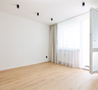 Interior of a 2-room apartment with a wooden decor floor, curtains, and open balcony doors.