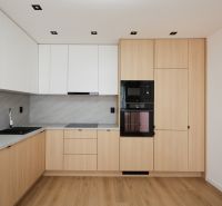 A kitchen in a 2-room apartment with white cabinets and a wood-patterned floor.