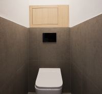 A toilet with neutral-toned tiles in a 2-room apartment.