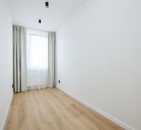 A room in a 2-room apartment with a wooden decor floor and a curtain.