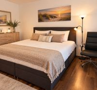 A bedroom in a family house with light furniture and a wooden decor floor.