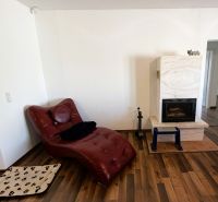A family house with a fireplace, a leather armchair, and a floor with a wooden decor.