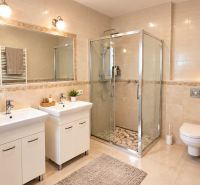 A bathroom with two sinks, a shower corner, and decorative tiles in a family house.
