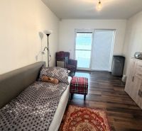 A room in a family house with a bed, an armchair, and a floor with a wood decor.