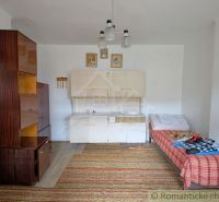 A room with simple furniture, a wooden decor floor, and a bed in a family house.